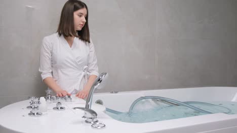 a young beautician at work. the girl adjusts the hydromassage bath before the procedure with the client. wellness massage.