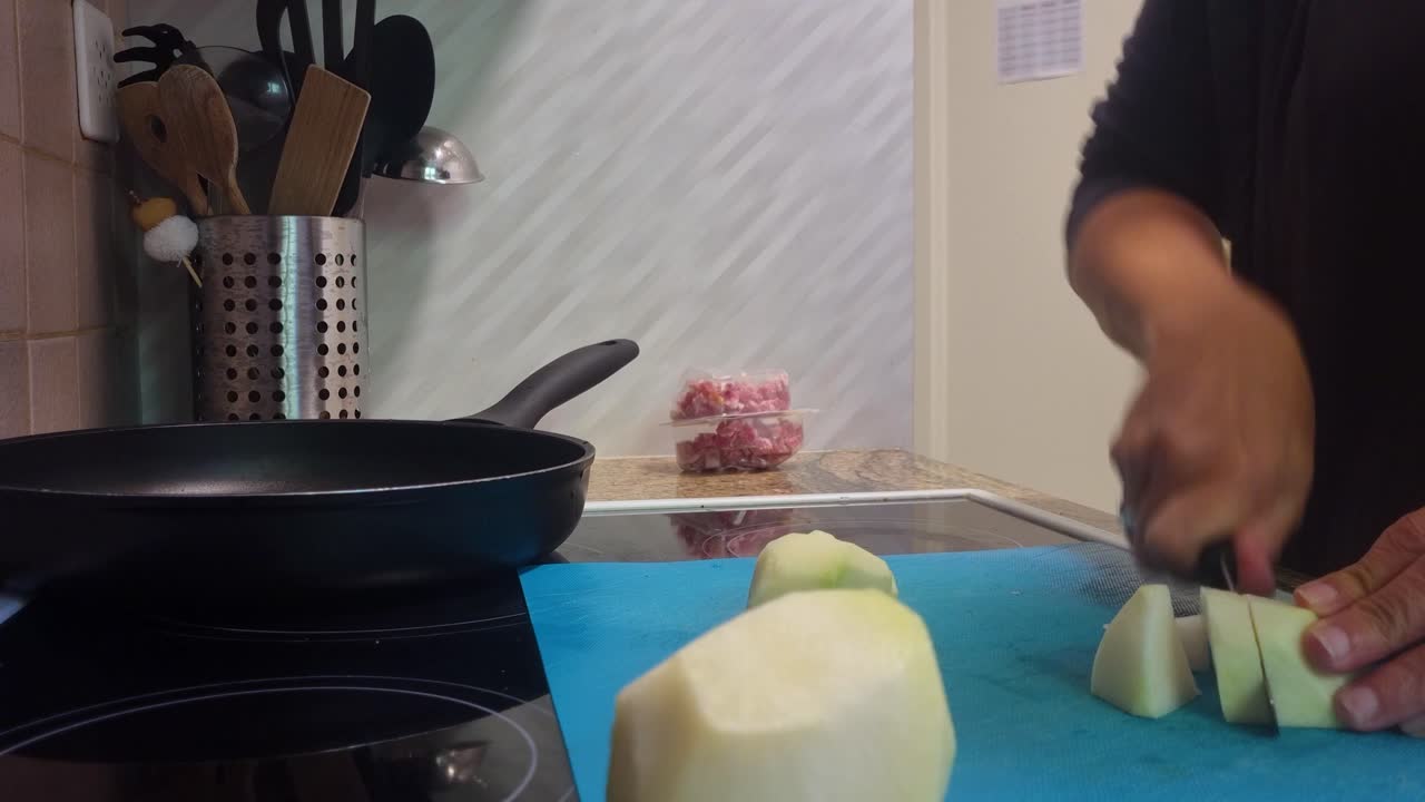 Home cooking scene where a woman slices two fresh kohlrabi (cabbage turnips) in her cozy kitchen, preparing a healthy meal with fresh vegetables, Switzerland, Europe