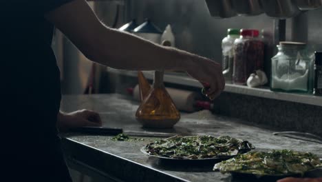 Pizza-maker-cutting-parsley-in-kitchen