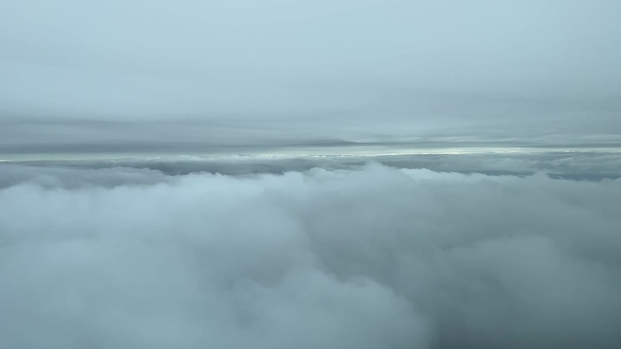 추운 겨울날 해변 근처에서 구름 사이를 비행하는 제트기 조종석에서 볼 수 있습니다.