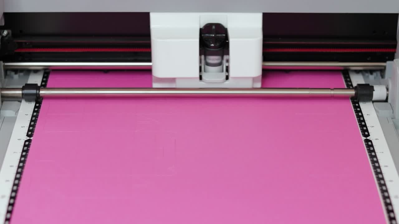 Cutting plotter precisely slices pink cardboard for crafting or packaging materials
