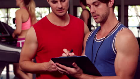 fit male trainer speaking with a muscular man