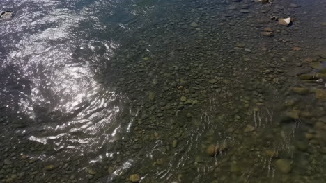 sunlight sparkling on clear river water with visible rocks