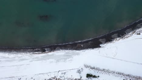 Turquoise-Blue-Ocean-And-Coast-Covered-With-White-Snow---Scenic-View-From-Above-In-Iceland---top-down-drone