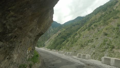 a vehicle passing through the most dangerous and narrow cliff-carved roads through the indian himalayas in kinnaur district on way to sangla and chitkul valley