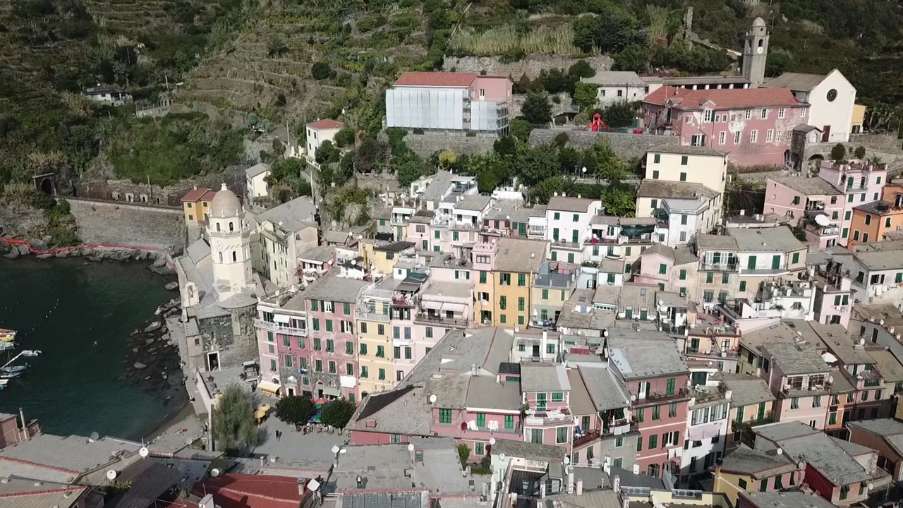 Drone view over Vernazza village and harbor with pastel buildings and the waterfront Church of Santa Margherita d’Antiochia, Cinque Terre, Liguria, Italy.