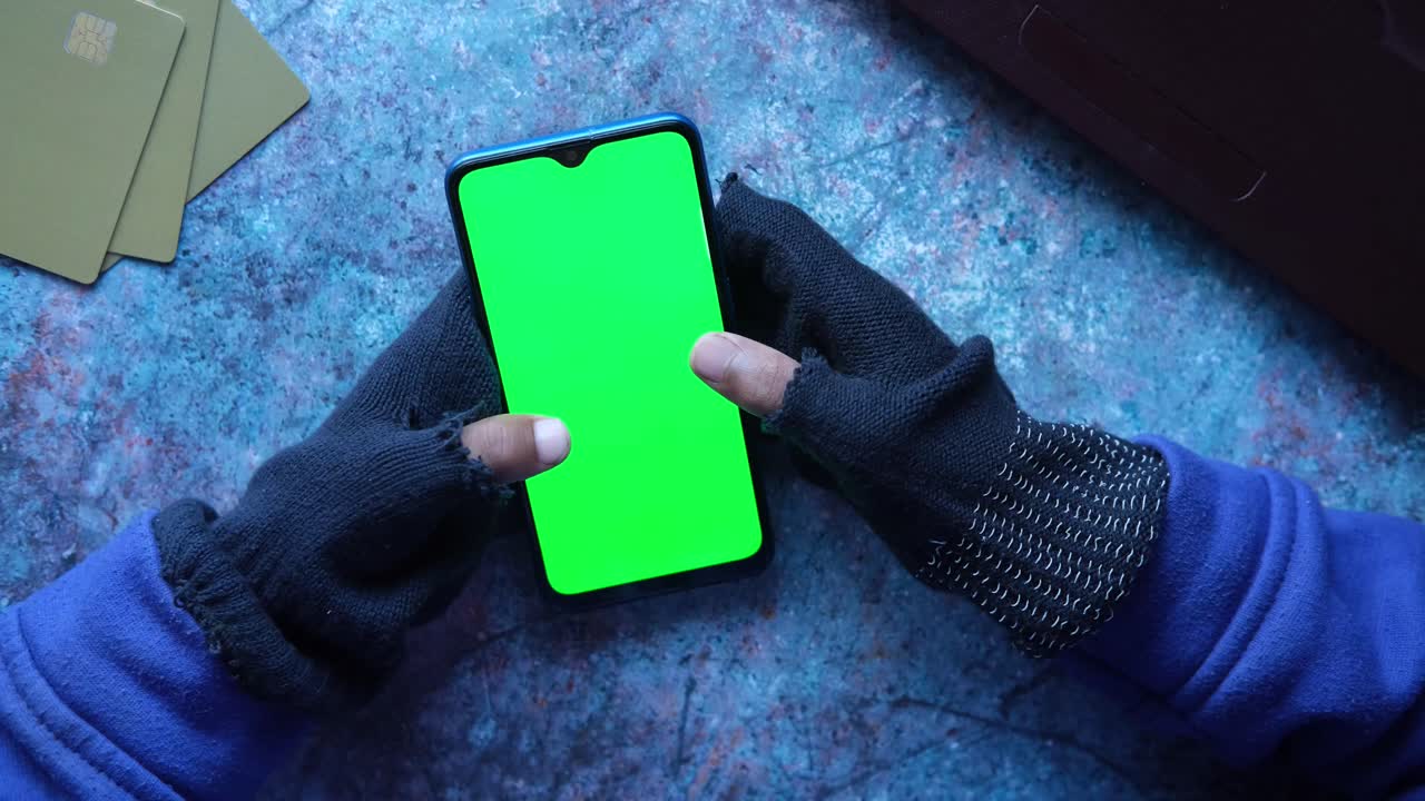 persona con guantes sosteniendo un teléfono inteligente con pantalla verde