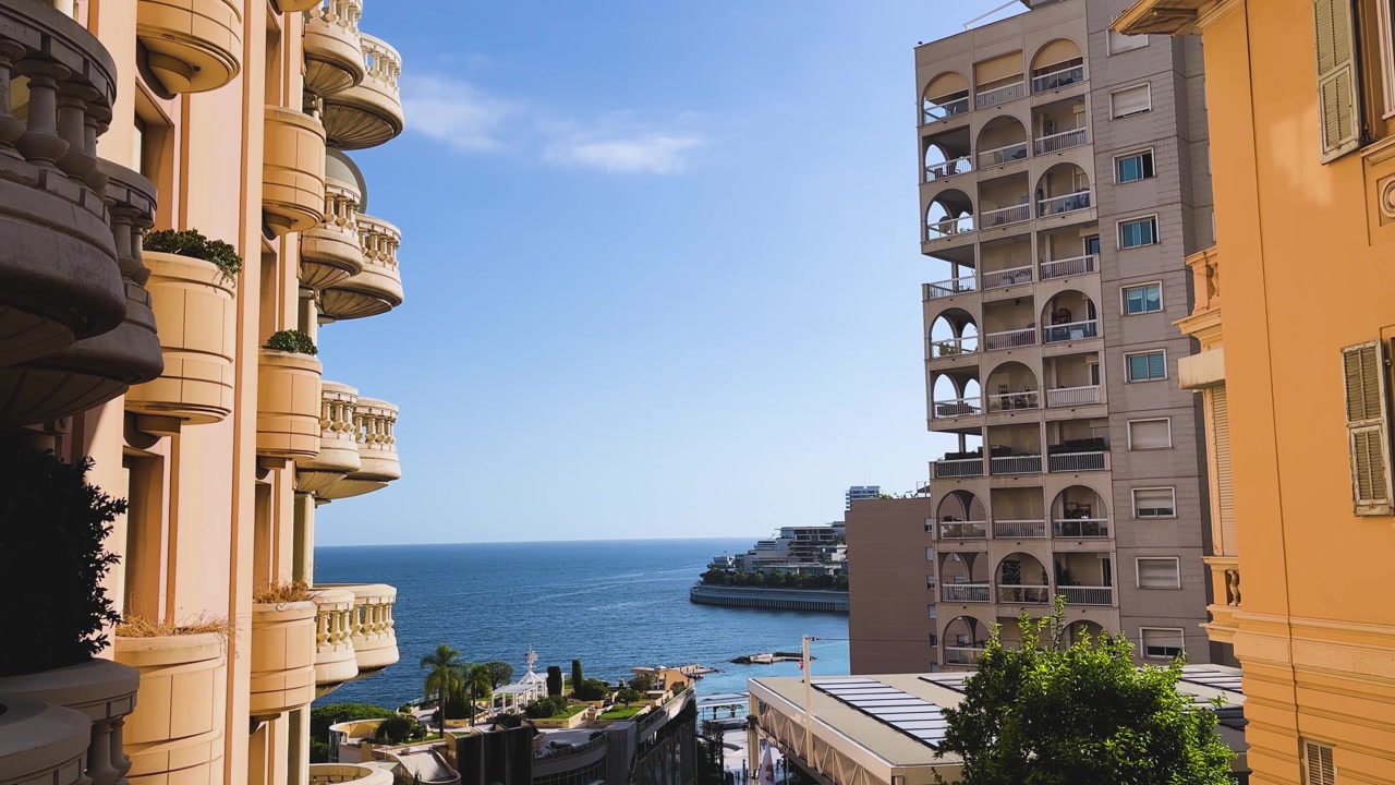 Vista mediterranea illuminata dal sole incorniciata da lussuosi edifici residenziali e balconi decorati a Monaco, che evidenzia l'elegante architettura costiera del principato