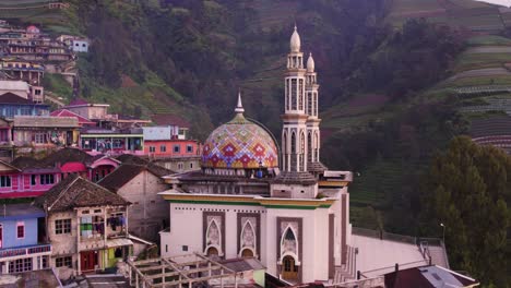 Low-angle-drone-shot-of-Mosque-of-nepal-van-java-and-peak-of-Mount-Sumbing,-aerial