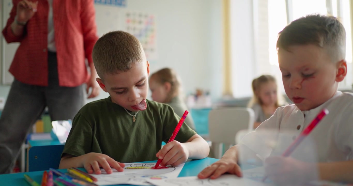 Focused Young Boys Coloring Pictures in a Classroom