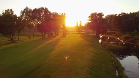 disparo aéreo de drones, ángulo bajo sobre el suelo en el campo de golf durante una puesta de sol increíble y soleada