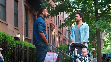 two young fathers with strollers talking in the street