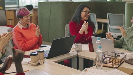 group of young colleagues clapping during meeting