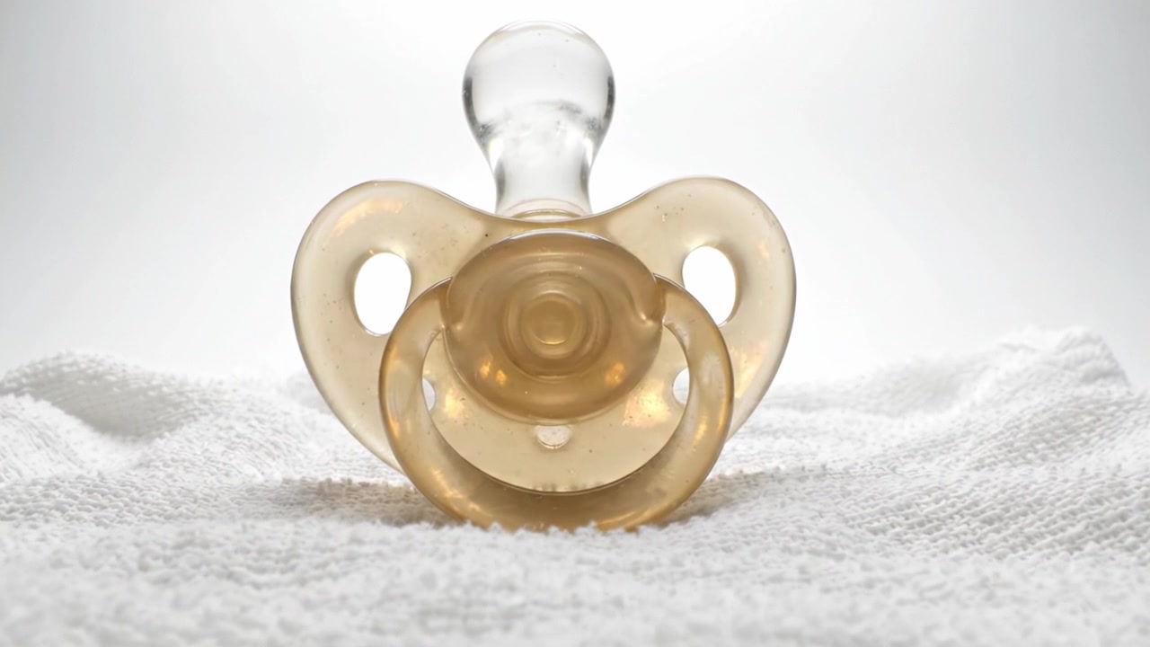 A Close-Up of a Baby Pacifier Resting on a Soft White Towel, Highlighting Its Shape and Texture in Soft Lighting for a Gentle Ambiance