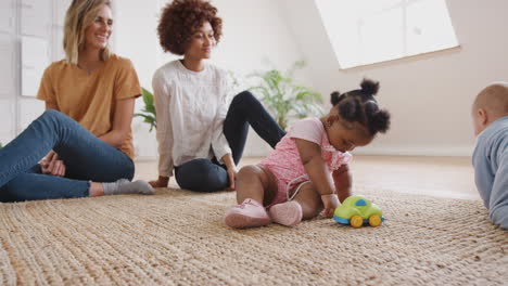 two mothers meeting for play date with babies at home in loft apartment