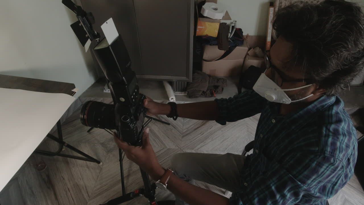 Indian Photographer sets up equipment in studio, focusing intently
