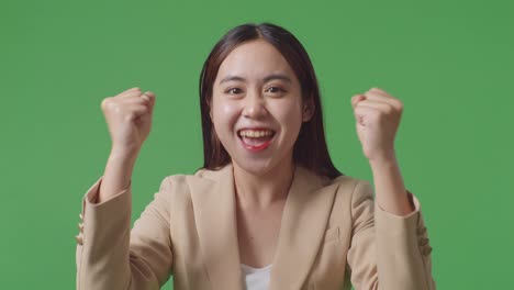 close up of happy asian business woman celebrating while standing on green screen in the studio