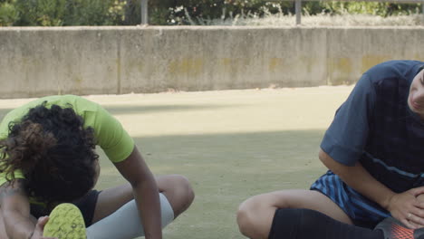 dolly shot of female football players sitting on the field and stretching legs