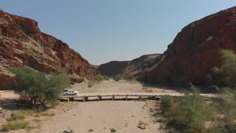 vehicle passing over bridge between mountain range dry river bed