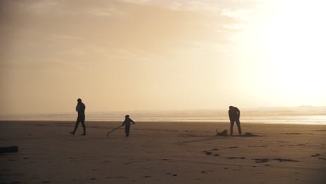 Imágenes-En-Cámara-Lenta-De-4k-De-Una-Familia-Jugando-En-La-Playa-Con-Su-Hijo-Mientras-Se-Pone-El-Sol---Disfrutando-Juntos-Del-Fin-De-Semana-De-Vacaciones