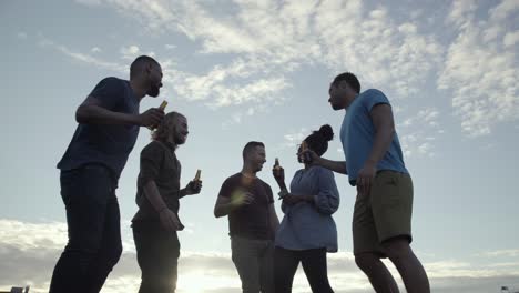 low angle view of young people clinking bottles and dancing