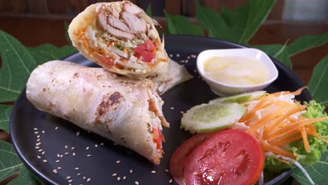 chicken kebab wrap on a black plate close up spinning