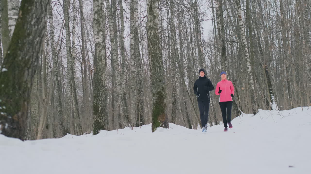 Man and woman run in the park in winter in slow motion
