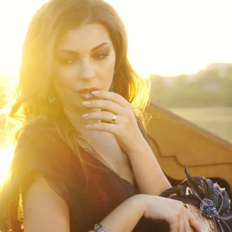 luxury mask with feathers in the hand of a gorgeous woman in carnival dress floating in a boat at sunset. attractive female in gondola with a mask in hand on the evening sun