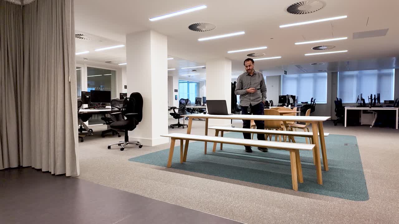 Esaurimento e pressione delle scadenze. Uomo solitario sud-asiatico che cammina nervosamente in un ufficio moderno guardando il laptop.