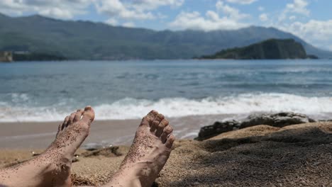 Man-with-sandy-feet-in-a-beautiful,-natural-beach,-Mediterranean