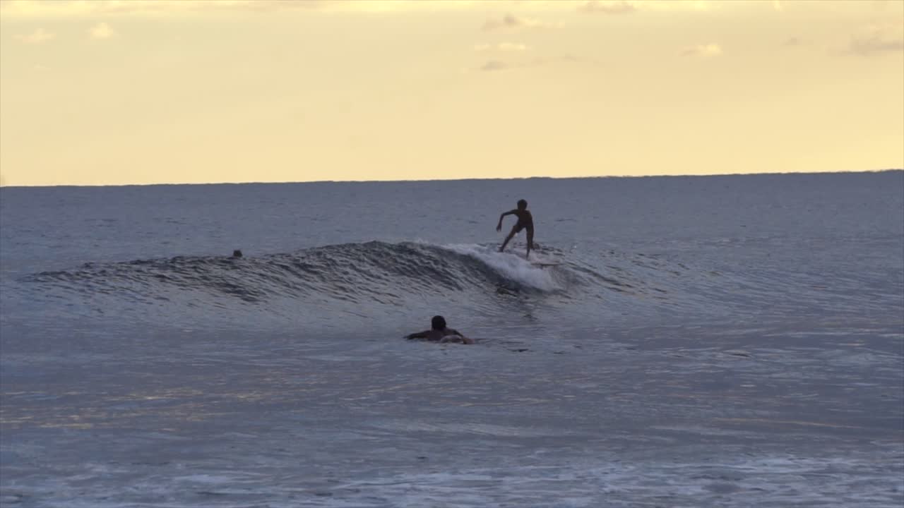 mo joven surfista atrapando olas en el atardecer de naranja quemada, indonesia