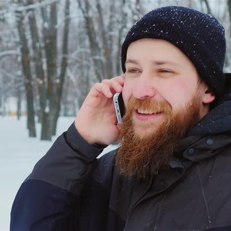 Hombre-Sonriente-Usa-Teléfono-Inteligente-En-El-Parque-De-Invierno