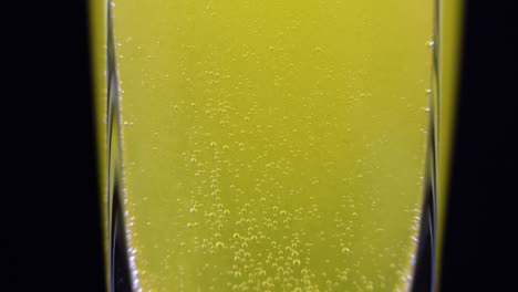cerca de la tableta de vitamina c disuelta en un vaso de agua mineral fresca en un fondo oscuro. tiro macro de líquido burbujeante amarillo con bolas de oxígeno