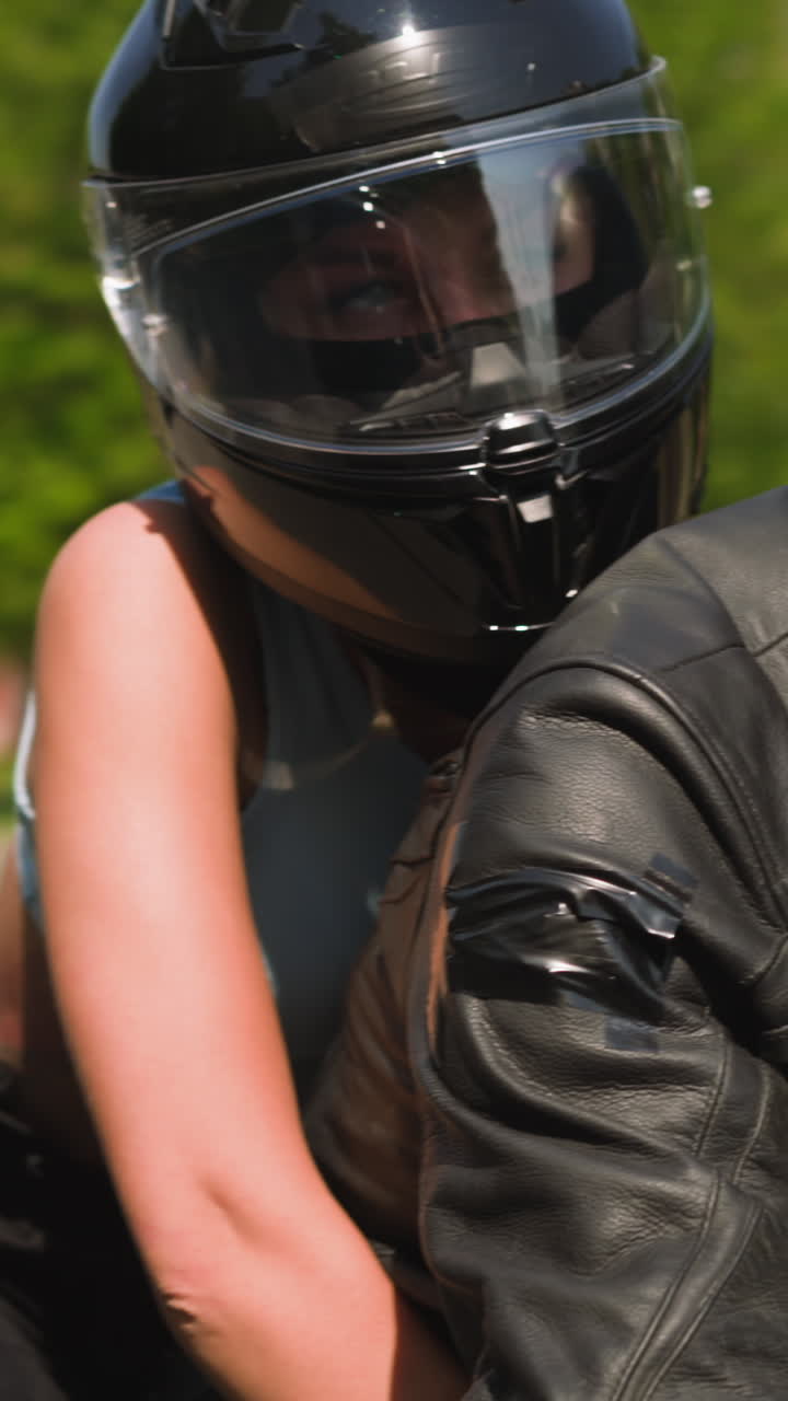 Young woman with helmet hugs boyfriend riding powerful motorcycle together along large city street on sunny spring day closeup slow motion