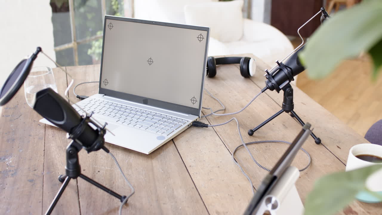 Podcast recording setup, laptop, microphones, and headphones on wooden table, copy space, at home