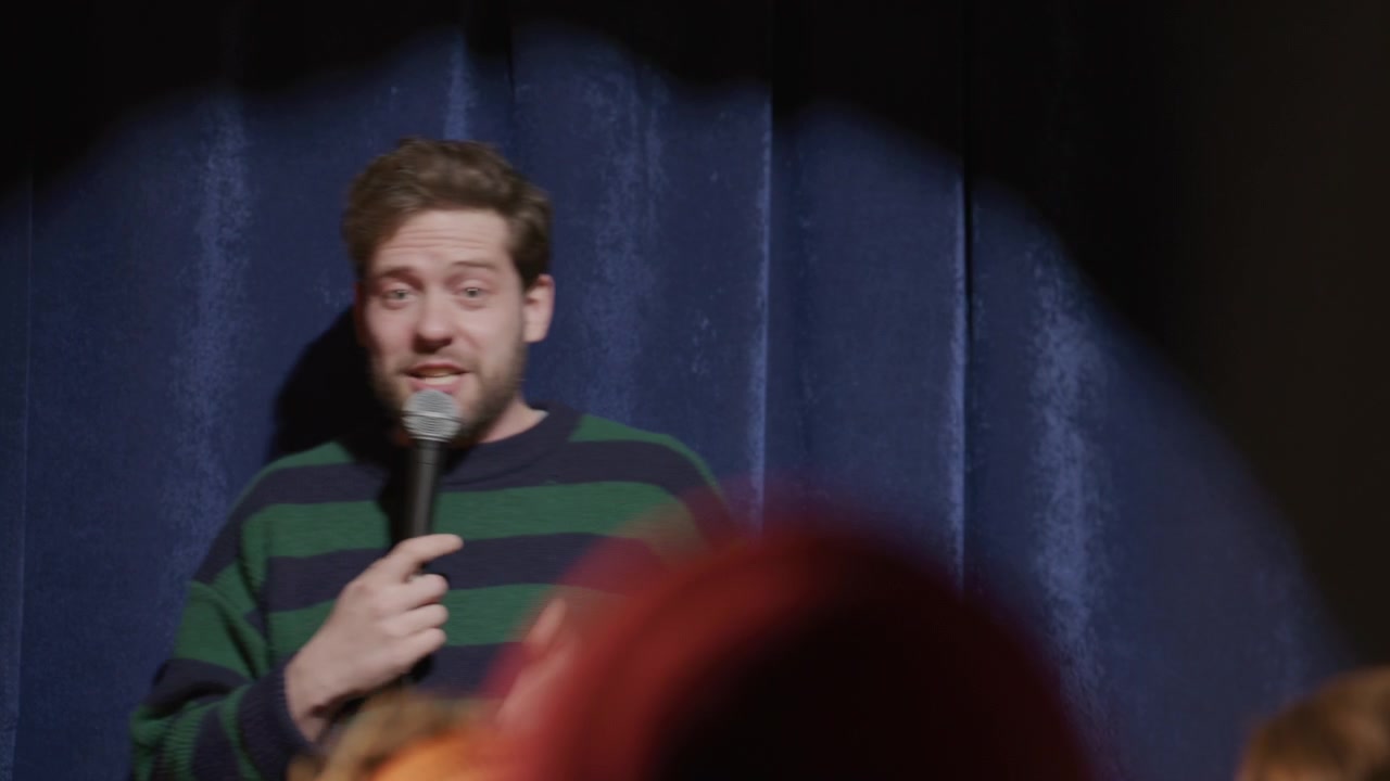 Comico che si esibisce in stand-up comedy con microfono durante un evento dal vivo