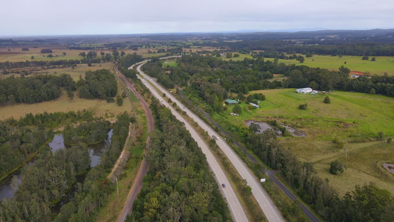 automóviles conduciendo en la autopista del pacífico pasando por campos verdes en el río johns en nueva gales del sur, australia