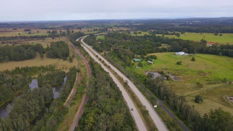 Automóviles-Conduciendo-En-La-Autopista-Del-Pacífico-Pasando-Por-Campos-Verdes-En-El-Río-Johns-En-Nueva-Gales-Del-Sur,-Australia