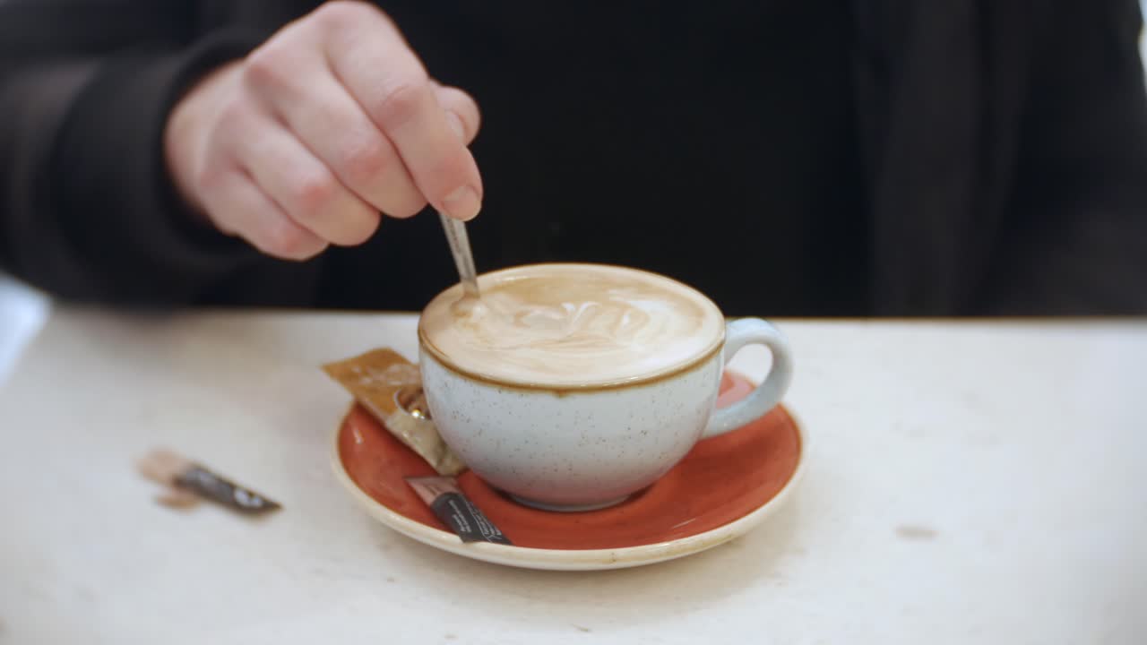 A woman is stirring her coffee in a cafe