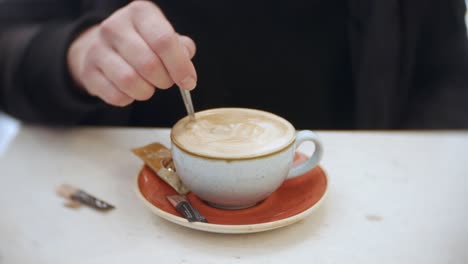 a woman is stirring her coffee in a cafe