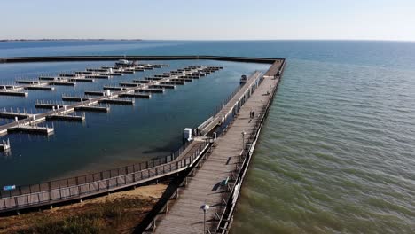 An-aerial-flyover-of-Harbor-Park-Pier-and-Marina-on-Lake-Huron-in-Tawas-City,-Michigan-on-a-sunny-autumn-day