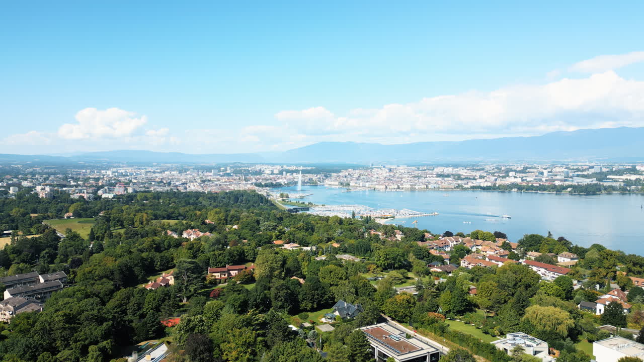 Aerial: water fountain of Geneva during the day (Rade of Geneva) from Cologny, Switzerland, push in drone shot