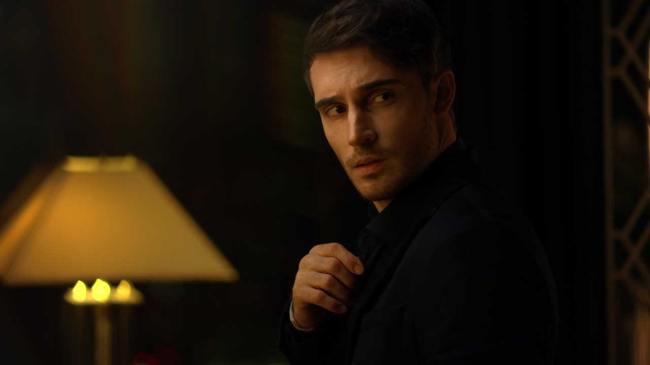 el gerente superior enderezando la camisa en el cuarto oscuro. hombre atractivo mirando a su alrededor.