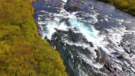 follow the flow of water by drone of the beautiful bruarfoss waterfall with turquoise water in iceland