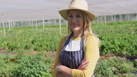 video of happy caucasian woman wearing apron and standing in greenhouse