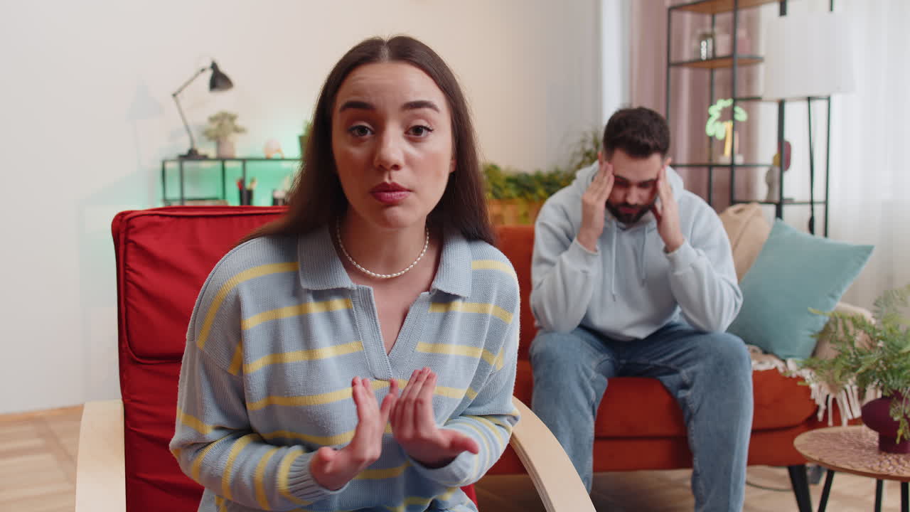 Aggressive woman talking to camera about quarreling with man at home conflict at family couple