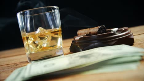 Cenicero,-Cigarro,-Whisky-Y-Dólares-Estadounidenses-En-La-Mesa-4k
