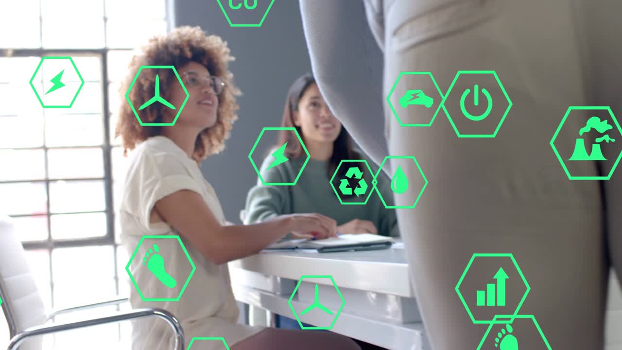 Donna riccia che prende appunti, collega in piedi che si sporge in avanti durante una riunione, mentre esaminano icone ecologiche sovrapposte.