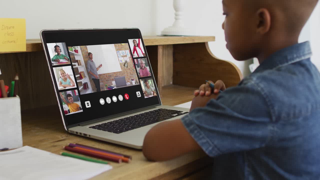 Afroamerikanischer Junge hält einen Bleistift und hat eine Videokonferenz am Laptop zu Hause.