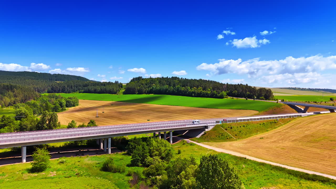 Cars and lorries run by the highways crossing a beautiful nature landscapes of Slovakia. Summer blue sky with some clouds in the sky. Aerial view